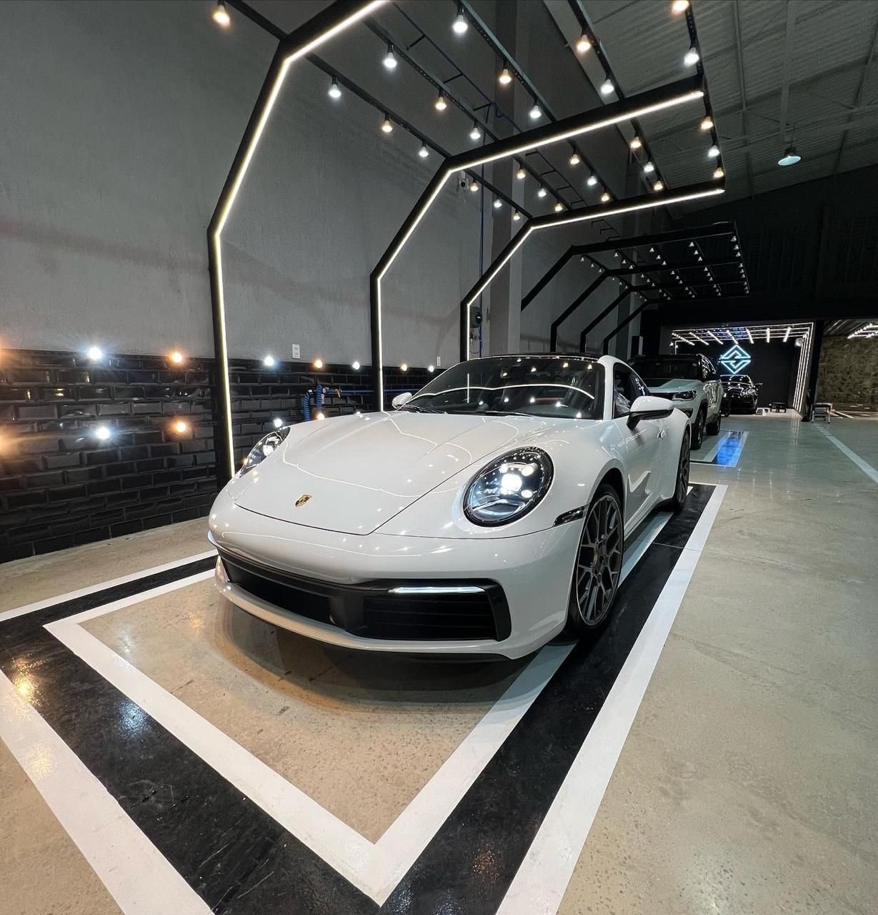Porsche 911 branco no box, sob os arcos de LED do estúdio