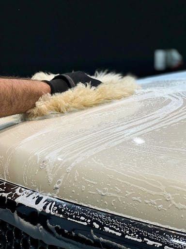 Luva de lã de carneiro deslizando no capô coberto de espuma
